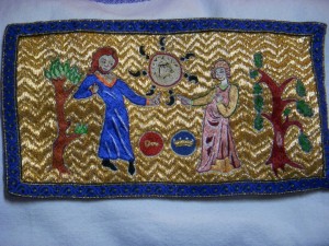 photo of couched embroidery showing two people, one with a coronet, the other with a seneschal symbol next to them, tossing a coin with 7 semi-colons around its edge